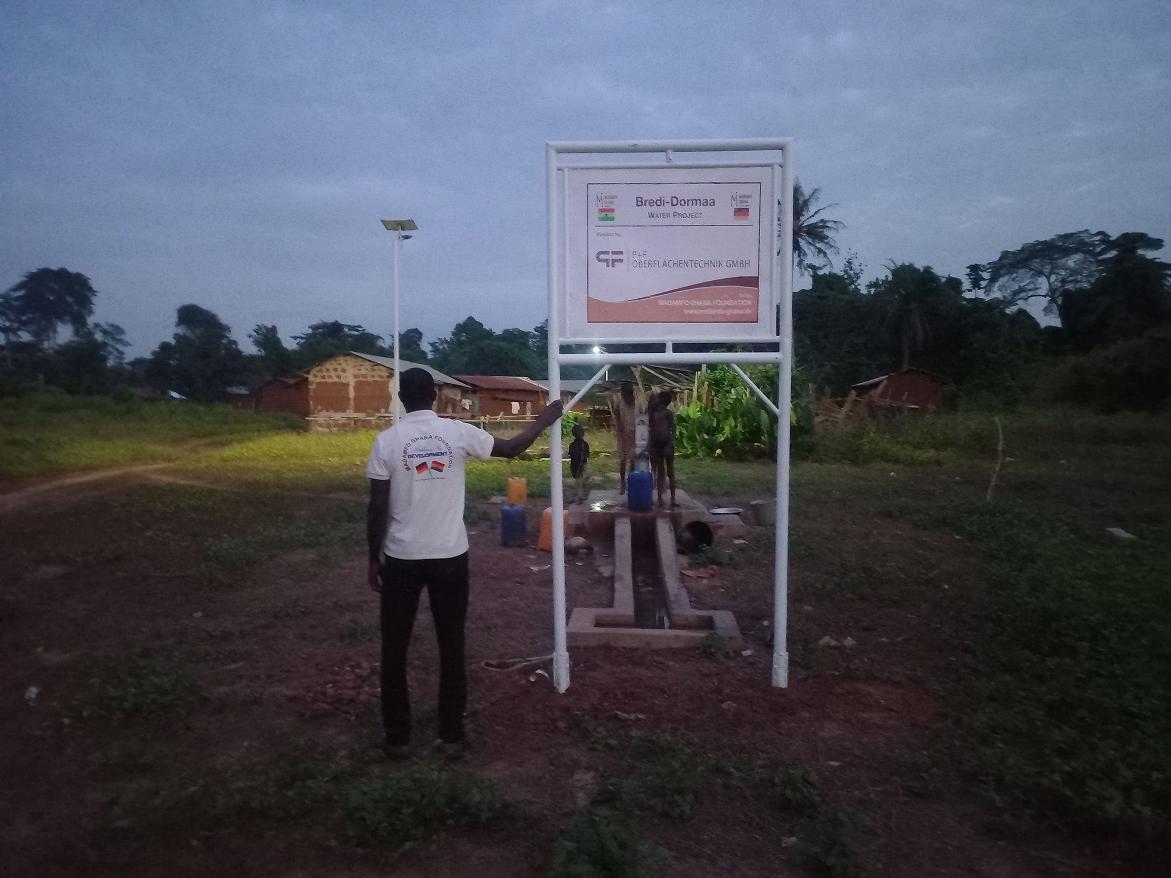 Soziale Verantwortung: Nutzung der Brunnenanlage bei Dämmerung im Projekt Madamfo Ghana