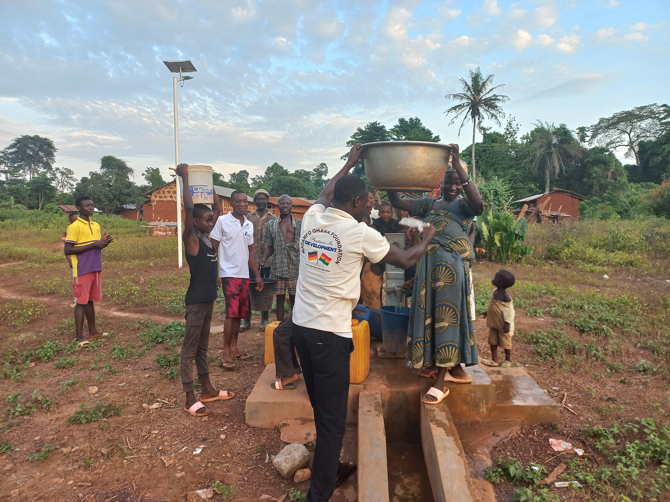Mehrere Menschen haben sich an der fertiggestellten Brunnenanlage versammelt, um Wasser zu holen.